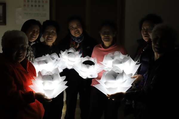 마을 주민들이 폐그물 업사이클링 전등을 설치하기 전 마을회관에서 기념촬영을 하고 있다.