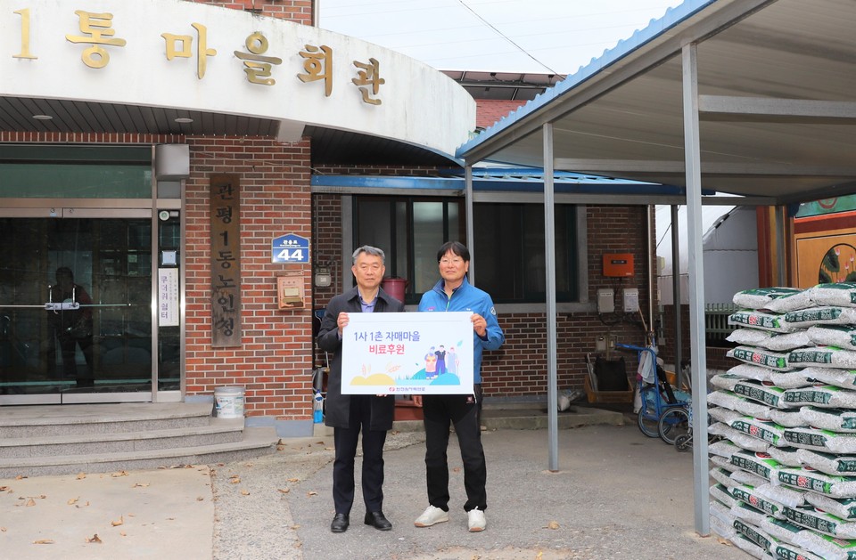 이선남 한전원자력연료 소통협력실장(왼쪽)이 김기성 관평동 통장에게 비료를 전달한 뒤 함께 기념촬영을 하고 있다.