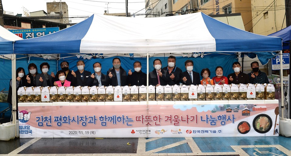 이배수 한전기술 사장(오른쪽에서 일곱 번째)과 김충섭 김천시장(오른쪽에서 다섯 번째)이 평화시장 상인회와 함께 손가락 하트로 응원의 메시지를 전하고 있다.